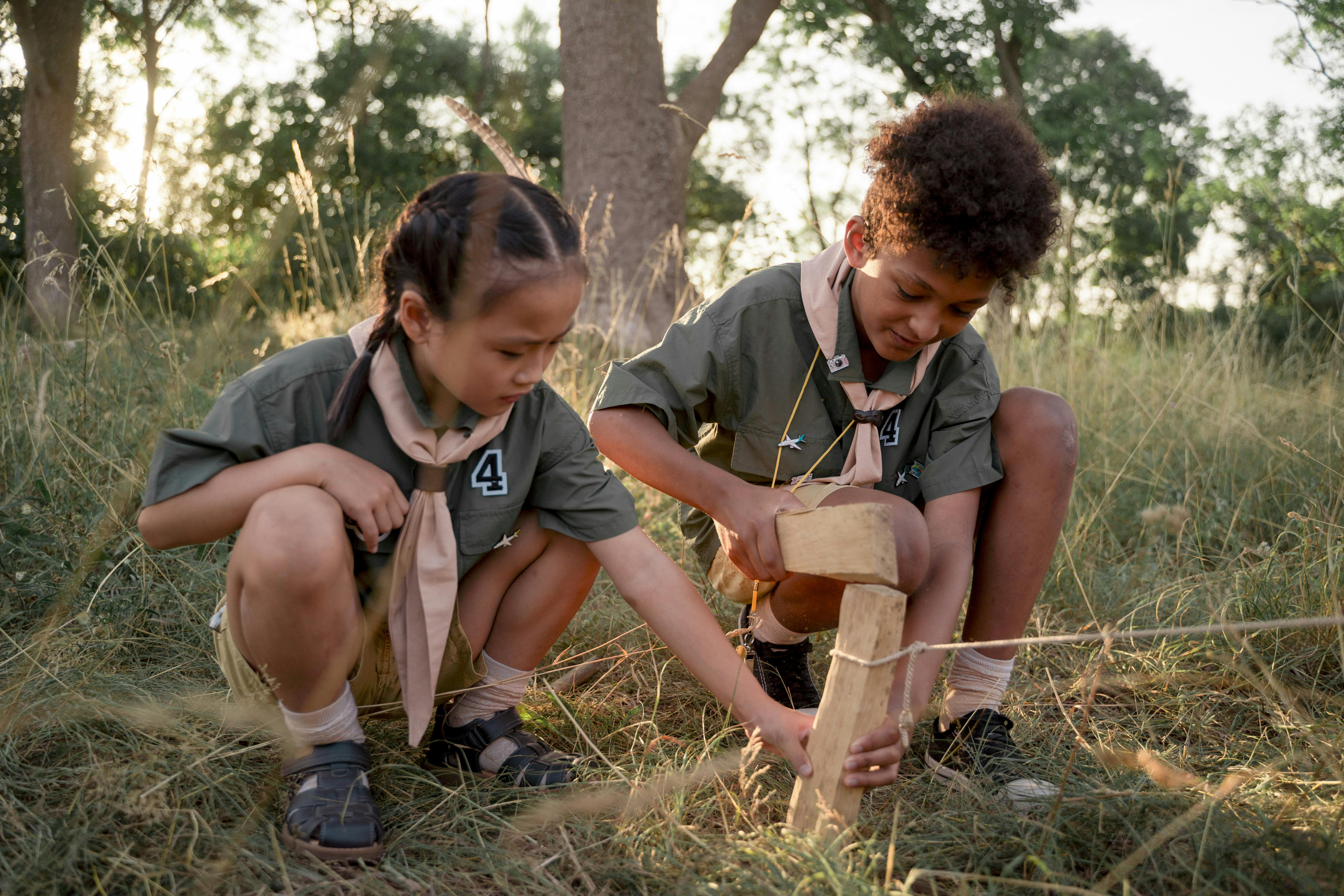 one boy and one girl crouching in a wood putting togethera structure