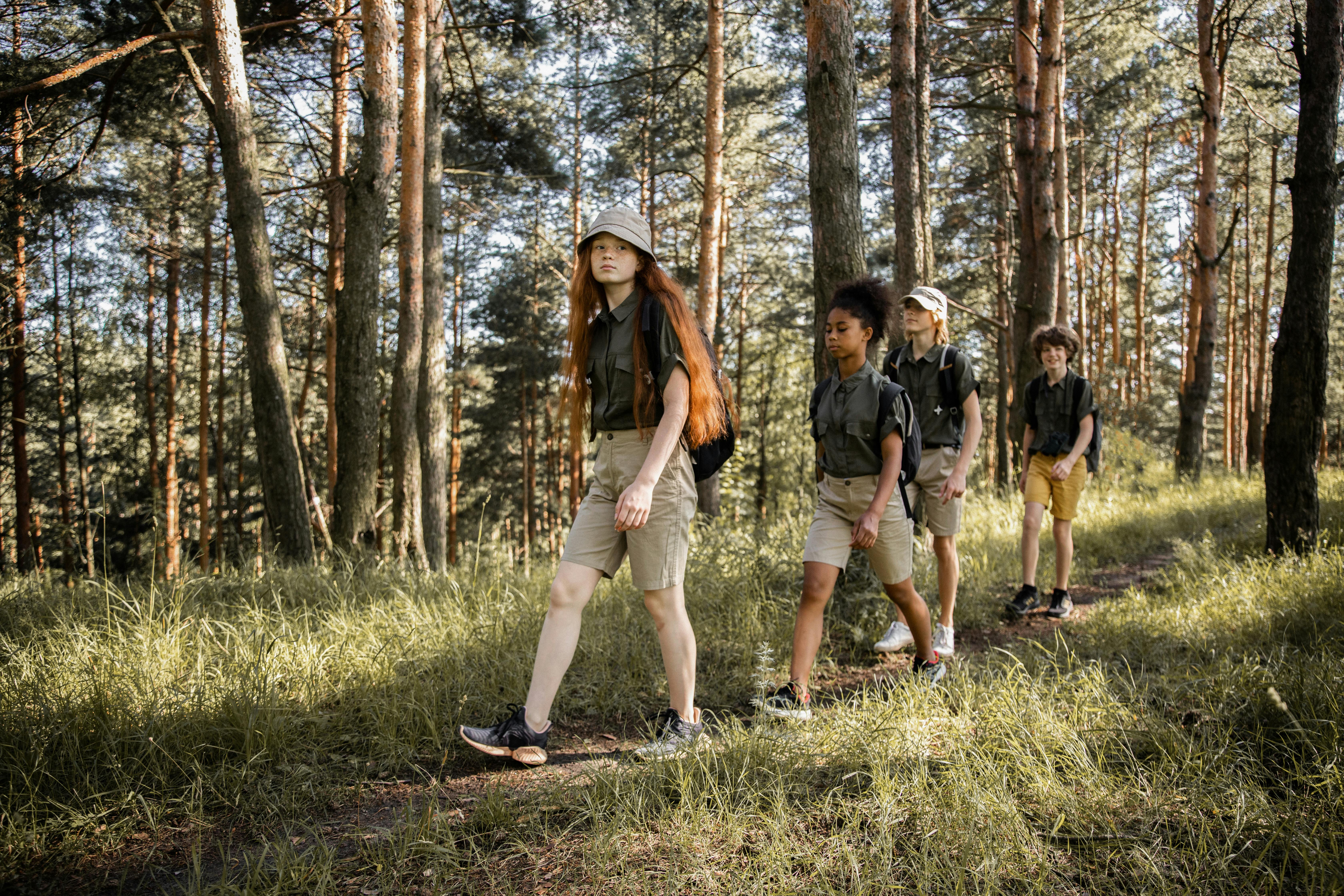 a group of two girls and two boys walking a line in a forest